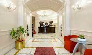 Tyylikäs hotelliaula, jossa on marmorilattia, tumma puupaneelinen vastaanottotiski ja tyylikäs kattokruunu. (Tekoälyn luoma teksti)