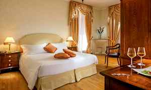 Tyylikäs hotellihuone, jossa on parivuode, koristeellisia tyynyjä ja puukalusteet. (Tekoälyn luoma teksti)