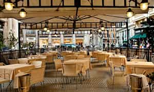 Kuva ulkoterassista, jossa on pöytiä ja tuoleja katoksen alla. (Tekoälyn luoma teksti)