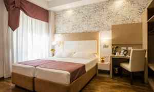 Hotellihuone, jossa on parivuode, työpöytä ja tuoli sekä koristeellisia yksityiskohtia. (Tekoälyn luoma teksti)