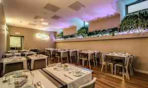 Katettu huone, jossa pöytiä ja tuoleja, koristeena kasveja ja valonlähteitä. (Tekoälyn luoma teksti)