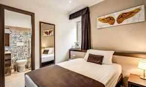 Hotellihuoneen sisustus, jossa on sänky ja avoin ovi kylpyhuoneeseen. (Tekoälyn luoma teksti)