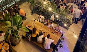 Ravintola, jossa ihmiset istuvat pöytien ääressä ja ruokailevat rennossa ilmapiirissä. (Tekoälyn luoma teksti)