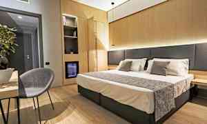 Hotellihuone, jossa parivuode, yöpöytä ja tuoli pöydän ääressä. (Tekoälyn luoma teksti)