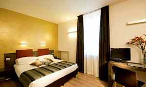 Hotellihuone, jossa on parivuode, työpöytä ja televisio. Huoneessa on vaaleat seinät ja suuri ikkuna tummilla verhoilla. (Tekoälyn luoma teksti)