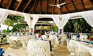 Ulkona sijaitseva ravintola, jossa on valkoiseksi maalattuja kalusteita ja puukatettu katto. (Tekoälyn luoma teksti)