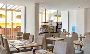 Ruokailutila, jossa katettuja pöytiä ja juoma-automaatteja. (Tekoälyn luoma teksti)