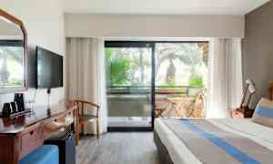 Kuva hotellihuoneesta, jossa on sänky, kirjoituspöytä ja parveke ulkokalusteineen. (Tekoälyn luoma teksti)