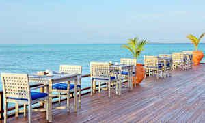 Ulkoterassi, jossa pöytiä ja tuoleja merenrannalla. (Tekoälyn luoma teksti)