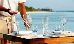 Ravintolan henkilökunta kattaa pöydän viinilaseilla rannalla. (Tekoälyn luoma teksti)