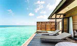 Ulkoilmaterassi, jossa aurinkotuoleja ja sininen meri taustalla. (Tekoälyn luoma teksti)