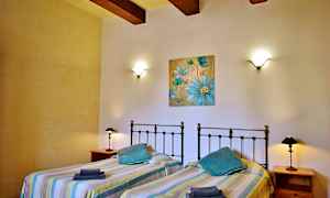 Makuuhuone, jossa on kaksi erillistä sänkyä, seinävalaisimet ja sininen kukkamaalaus seinällä. (Tekoälyn luoma teksti)