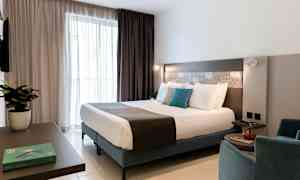 Moderni hotellihuone, jossa on parivuode, istuinalue ja sisustusyksityiskohtia. (Tekoälyn luoma teksti)