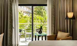 Hotellihuone, jossa näkymä vehreälle parvekkeelle. (Tekoälyn luoma teksti)