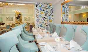 Tyylikäs ruokasali, jossa on vaaleansiniset tuolit ja koristeelliset pöydät. (Tekoälyn luoma teksti)