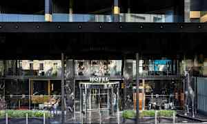 Hotellin etupuoli, jossa on lasiovet ja koristeellinen hopeanvärinen kirahvipatsas sisäänkäynnin vieressä. (Tekoälyn luoma teksti)