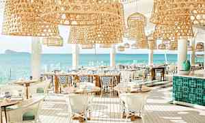 Valoisa ravintola, jossa rottinkivalaisimet ja näkymät merelle. (Tekoälyn luoma teksti)