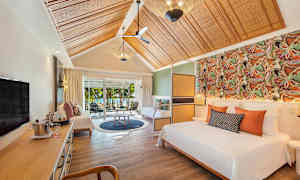 Tyylikäs hotellihuone, jossa sänky, oleskelutila ja näkymä puutarhaan liukuovien läpi. (Tekoälyn luoma teksti)