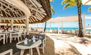 Avoin ravintola rannalla, jossa on valkoiset kalusteet ja näköala merelle. (Tekoälyn luoma teksti)