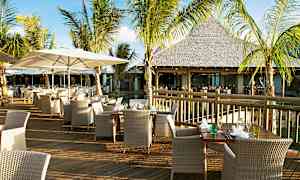 Ulkona sijaitseva ravintola, jossa on pöytiä ja tuoleja puuterassilla palmujen ympäröimänä. (Tekoälyn luoma teksti)