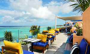 Ulkoterassi aurinkotuoleilla ja pöydillä meren äärellä. (Tekoälyn luoma teksti)