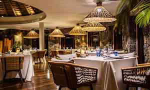 Tyylikäs ravintola, jossa on katettuja pöytiä ja rottinkilamppuja. (Tekoälyn luoma teksti)