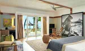 Modernisti sisustettu hotellihuone, lasiovet avautuvat rannalle ja palmupuille. (Tekoälyn luoma teksti)