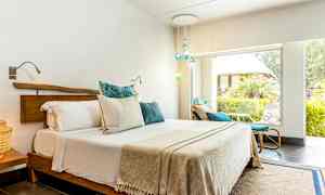 Valoisa makuuhuone, jossa on parivuode ja suuret ikkunat vehreään puutarhaan. (Tekoälyn luoma teksti)