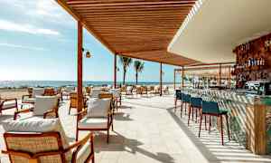 Ulkoterassi, jossa on istumapaikkoja ja baari puukatoksen alla rannalla. (Tekoälyn luoma teksti)