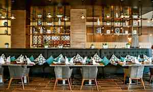 Ravintolaympäristö, jossa pöytiä, tuoleja ja seinäkoristeita hyllyillä. (Tekoälyn luoma teksti)