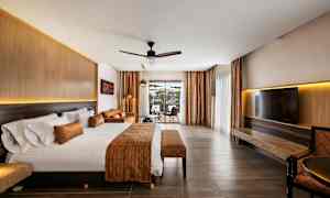 Hotellihuone, jossa suuri sänky, oleskelutila ja näkymä lasiovien läpi. (Tekoälyn luoma teksti)