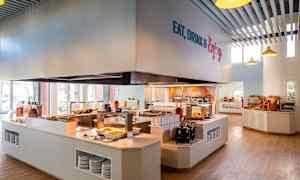 Itsepalvelukahvila, jossa ruokia on esillä tiskeillä ja leipävalikoima näkyy hyllyillä. (Tekoälyn luoma teksti)