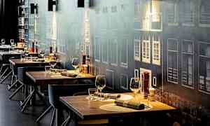 Useita katettuja ravintolapöytiä, joissa on lasit ja aterimet, seinän edessä, jossa on julkisivukuva. (Tekoälyn luoma teksti)