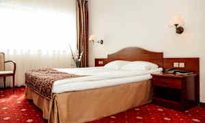 Hotellihuone, jossa sänky, yöpöytä ja verhot. (Tekoälyn luoma teksti)