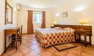 Hotellihuone, jossa on kaksi erillistä vuodetta ja seinän vieressä työpöytä. (Tekoälyn luoma teksti)