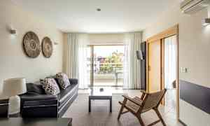 Moderni olohuone, jossa sohva, puutuoli ja pääsy parvekkeelle lasioven kautta. (Tekoälyn luoma teksti)