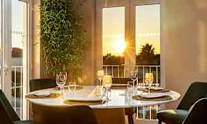 Pöytä katettuna ikkunan äärellä, näkymä auringonlaskuun. (Tekoälyn luoma teksti)