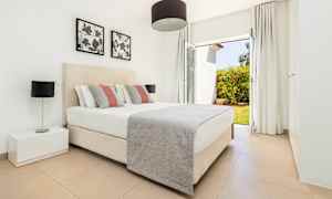 Makuuhuone, jossa on parivuode, yöpöytä ja ikkuna, josta on näkymä puutarhaan. (Tekoälyn luoma teksti)