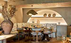 Tyylikäs ravintolapöytä, jota ympäröivät tuolit ja penkit geometrisilla kuvioiduilla tyynyillä. (Tekoälyn luoma teksti)