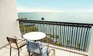 Parveke, jossa pöytä, tuoli ja raidallinen pyyhe, merinäköalalla. (Tekoälyn luoma teksti)