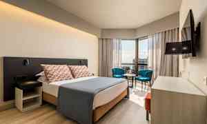 Moderni hotellihuone, jossa parivuode, oleskelutila ja näkymä. (Tekoälyn luoma teksti)