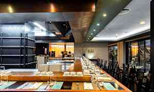 Kuvassa nykyaikainen ravintola, jossa on katettu pöytä ja avokeittiö. (Tekoälyn luoma teksti)