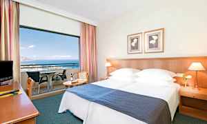 Hotellihuone, jossa parivuode, yöpöytä ja parveke merinäköalalla. (Tekoälyn luoma teksti)