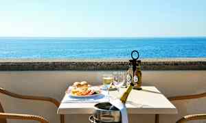 Näkymä merelle terassilta, jossa on katettu pöytä ruoan ja juoman kanssa. (Tekoälyn luoma teksti)