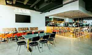 Ravintolan sisustus, jossa pöytiä, tuoleja ja baaritiski. (Tekoälyn luoma teksti)