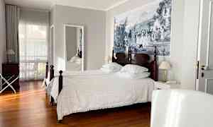 Hotellihuone, jossa on kaksi yhden hengen sänkyä, puulattia ja suuri seinämaalaus. (Tekoälyn luoma teksti)