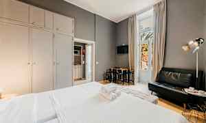 Hotellihuone, jossa on sänky, sohva ja ruokapöytä, suuret vaatekaapit sekä parvekeovi. (Tekoälyn luoma teksti)