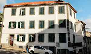 Rakennus, jossa valkoiset seinät, vihreät ikkunaluukut ja punaiset kattotiilet. (Tekoälyn luoma teksti)