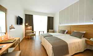 Hotellihuone, jossa kaksi erillistä vuodetta, kirjoituspöytä ja istumapaikkoja. (Tekoälyn luoma teksti)