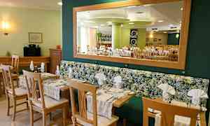 Ravintola, jossa pöytiä ja tuoleja sekä peili seinällä. (Tekoälyn luoma teksti)